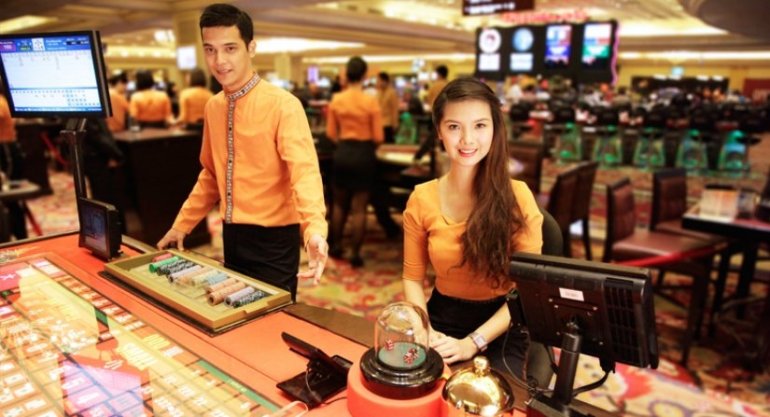 Двое крупье азиатов за столом для игры в сик бо в зале казино