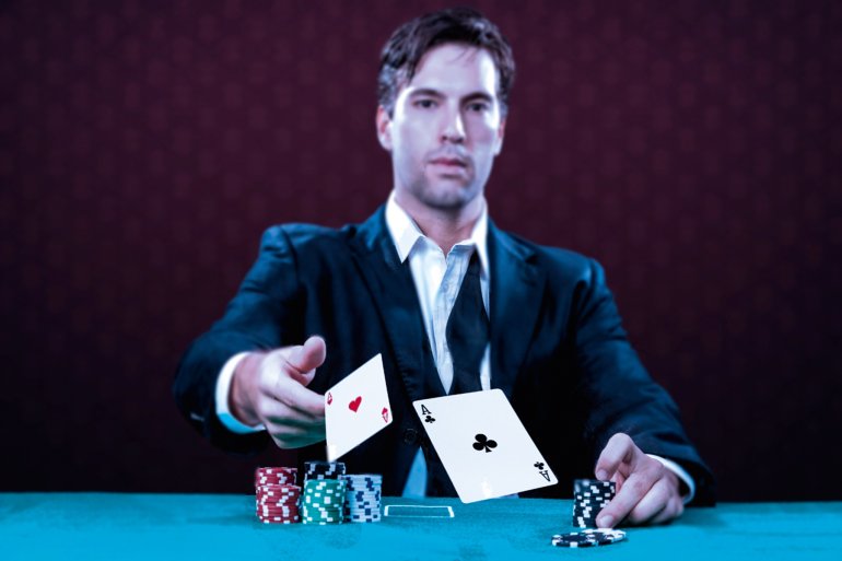 Мужчина в строгом костюме бросает карты на игорный стол