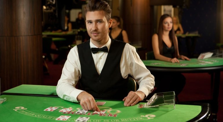 Молодой парень дилер казино холдем покера ждет клиентов за столом