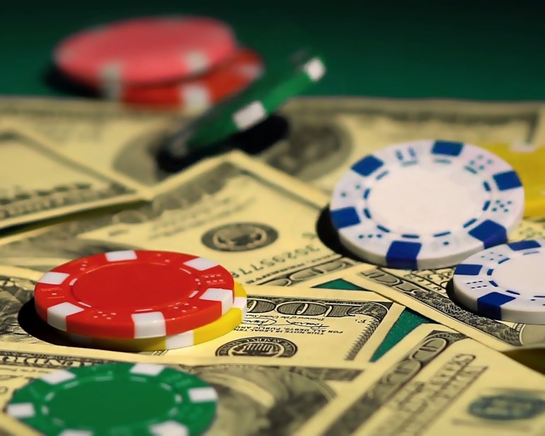 Стодолларовые купюры и фишки казино вперемешку