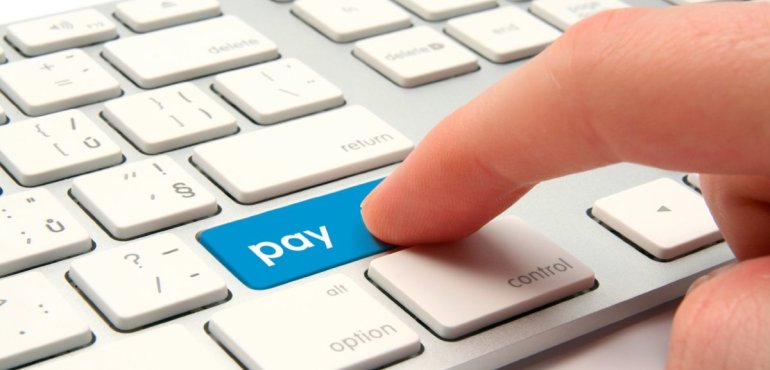 Палец жмет синюю кнопку с надписью "Pay" на клавиатуре ноутбука